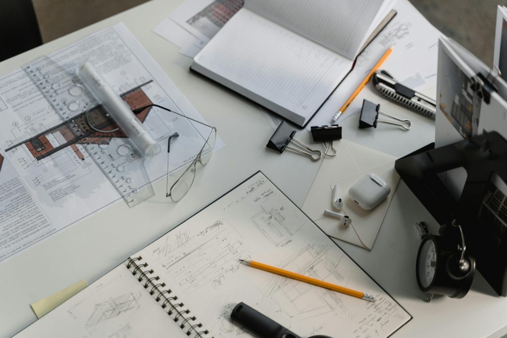 A busy architectural workspace featuring blueprints, sketches, and drafting tools.